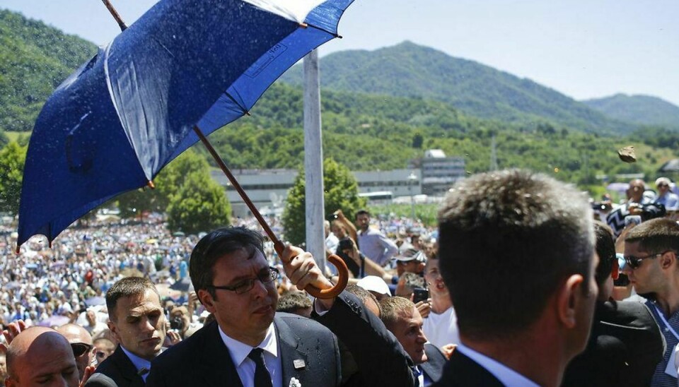 Serbiens premierminister Aleksandar Vucic bliver beskyttet med en paraply unde en mindehøjtidelighed for massakren i Srebenicha lørdag. Foto: Stoyan Nenov/Scanpix