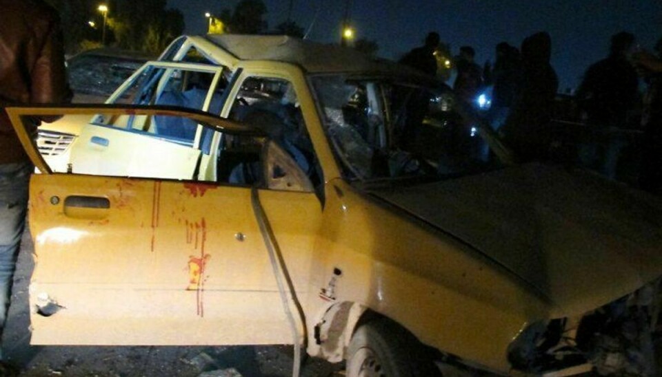 Irakiske mænd kigger på det sammenkrøllede vrag af den bil, der onsdag eksploderede i Bagdad. Torsdag har endnu en bilbombe kostet snesevis af mennesker livet i den irakiske hovedstad. Foto: Amer al-Saadi/Scanpix
