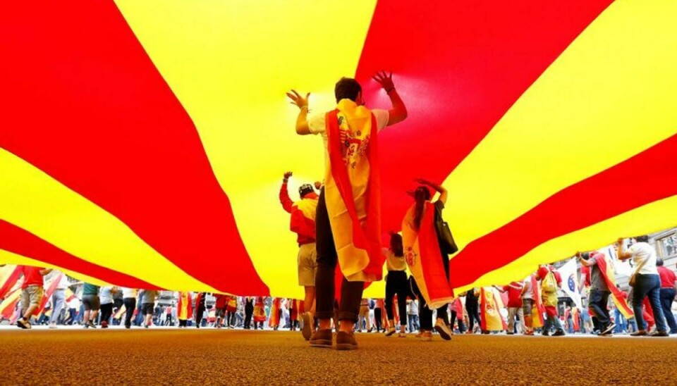 ARKIV. People walk under a huge Catalan flag during Spain’s National Day in Barcelona, Spain, October 12, 2017. PLUS Spaniens regering gør klar til at tage magten fra selvstyret i Catalonien, som stadig truer med løsrivelse. Ingen vil være skyld i, at krisen eskalerer. REUTERS/Gonzalo Fuentes TPX IMAGES OF THE DAY