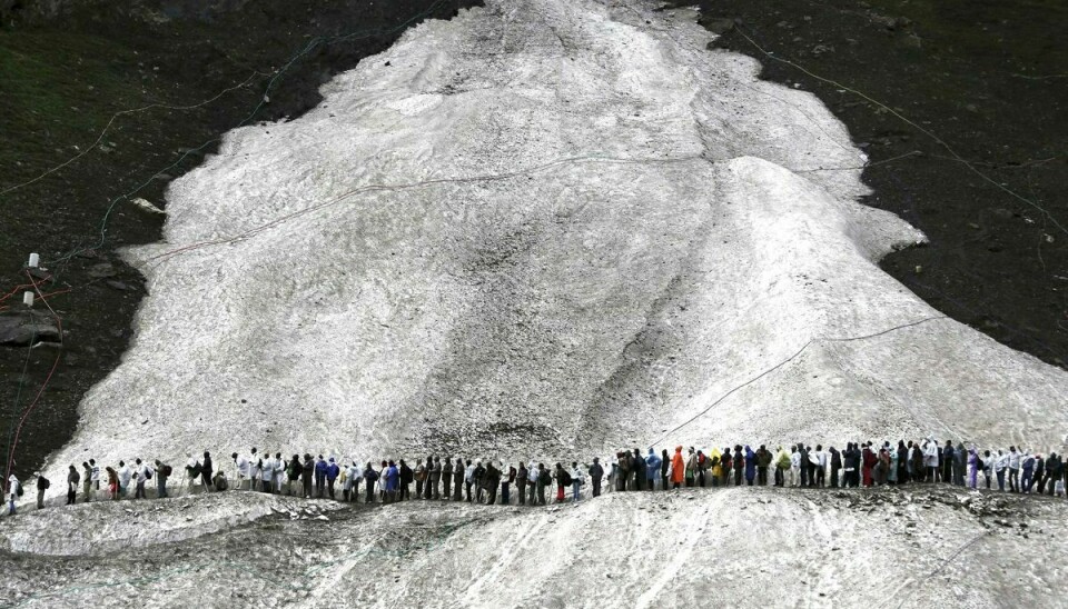 På dette billede fra 2012 kan man se, hvordan pilgrimme må krydse is og sne for at nå til fjerntliggende hule i Himalaya.