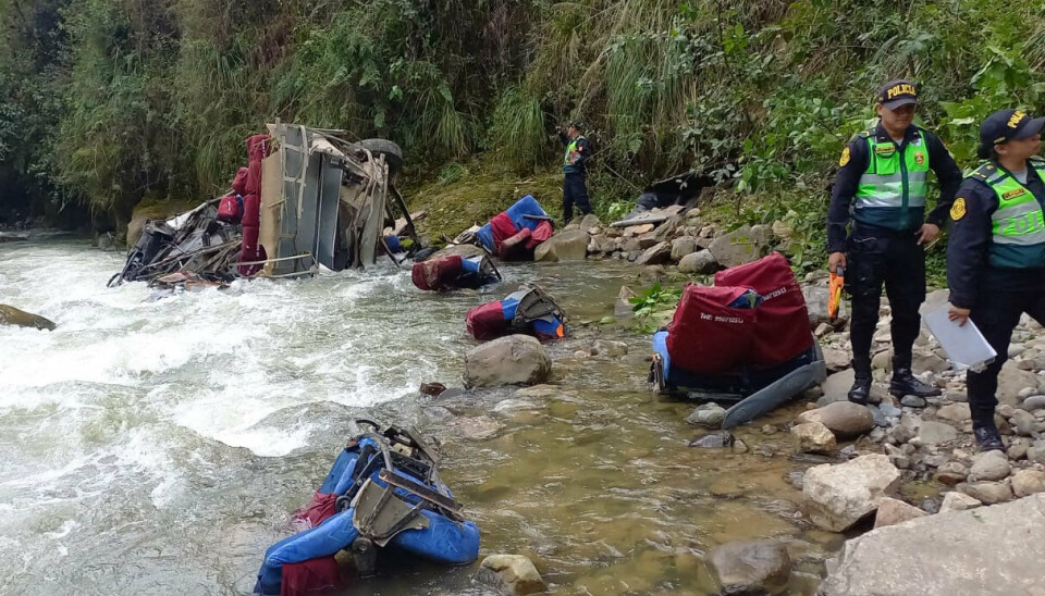 Politi i Peru har udsendt et billede af betjente, der undersøger det sted, hvor en bus faldt fra en vej i bjergene ned i en flod.