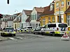 Flere danske politibiler spærrer en bygade med afspærringsbånd