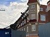 Rød murstensbygning med skiltet Fredens Hus bag blå byggeafskærmning.