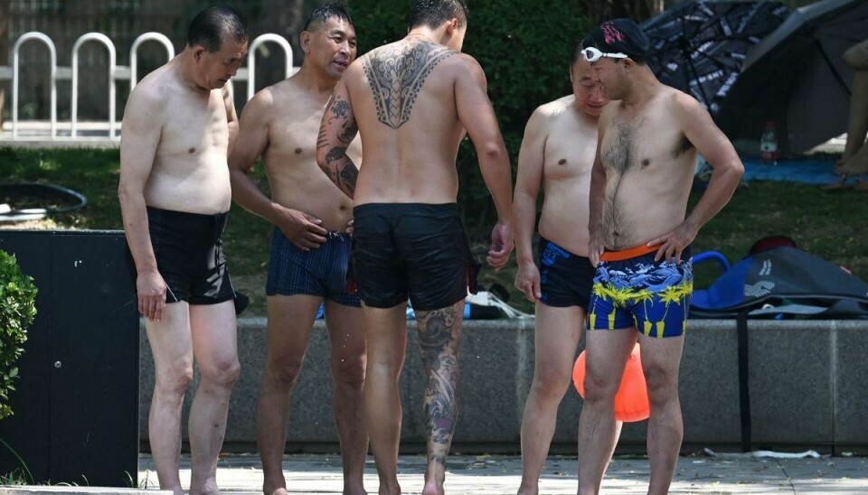 Mænd svømmer i en kanal i Beijing, mens Kina er truet af voldsomme varmegrader.
