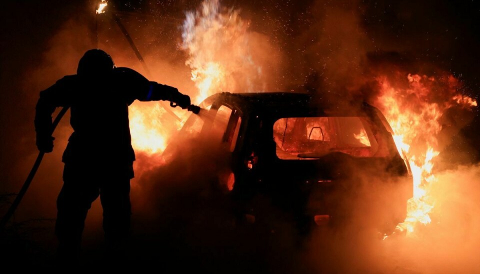 Her ses en brandmand i gang med at slukke en brand i en bil lørdag under uroligheder i landet. (Arkivfoto).