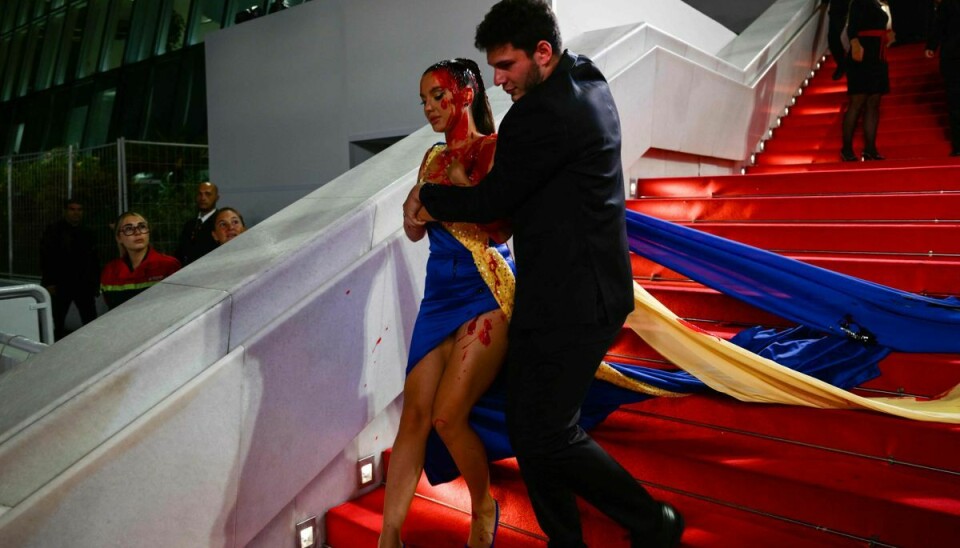 Der har været to optrin i Cannes, hvor kvindelige demonstranter har smurt sig selv ind i blod i forbindelse med krigen i Ukraine. Her ses kvinden, der er klædt i en kjole i det ukrainske flags farver. Kort forinden har hun hældt teaterblod ud over sig selv.