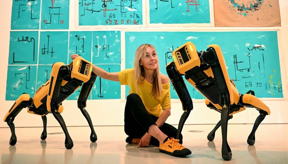 Den polske kunstner Agnieszka Pilat poserer med kunstværket af sine robotmalende hunde - Basia Spot og Bunny Spot - som er blevet kunstnere, der maler på lærred med poterne, ved lanceringen af ​​National Gallery of Victoria (NGV) Triennial 2023 i Melbourne den 5. april, 2023.