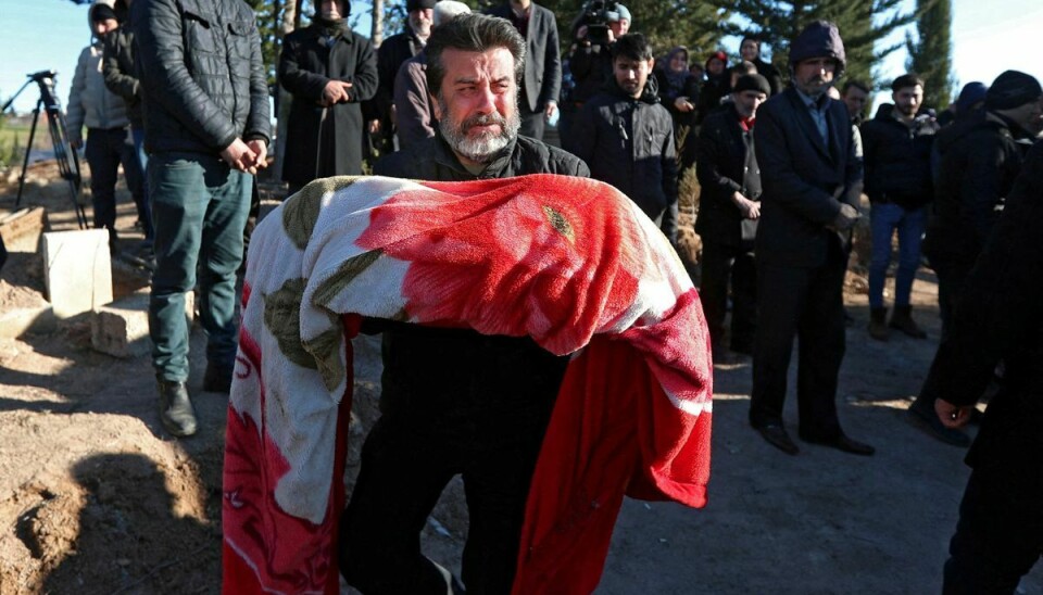 En mand bærer liget af et barn, der blev dræbt sammen med sine forældre i jordskælvene, der ramte Tyrkiet mandag.