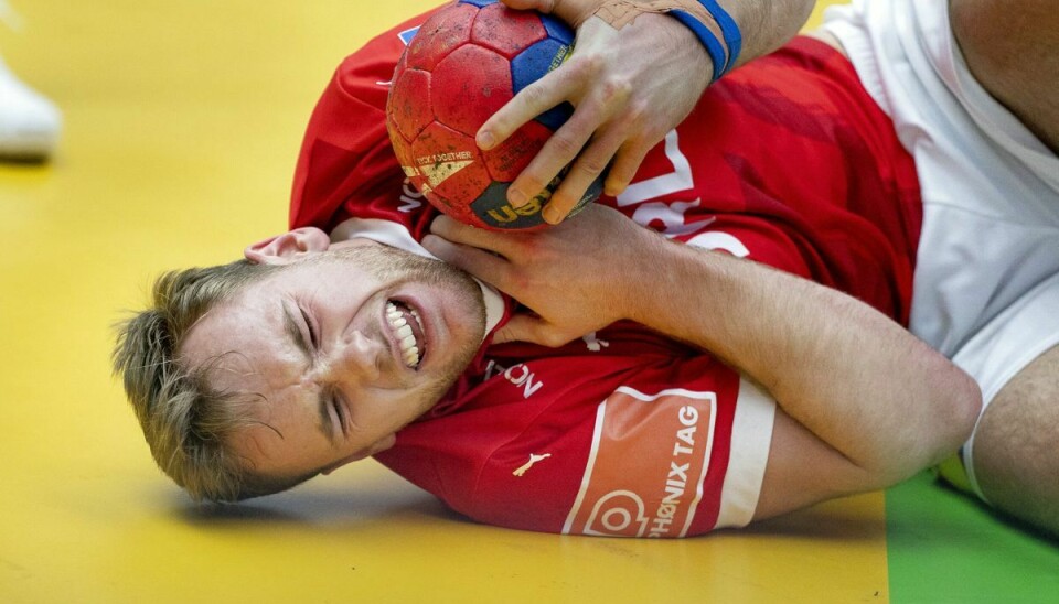 Mathias Gidsel vred sig på gulvet efter at have modtaget et slag på halsen.