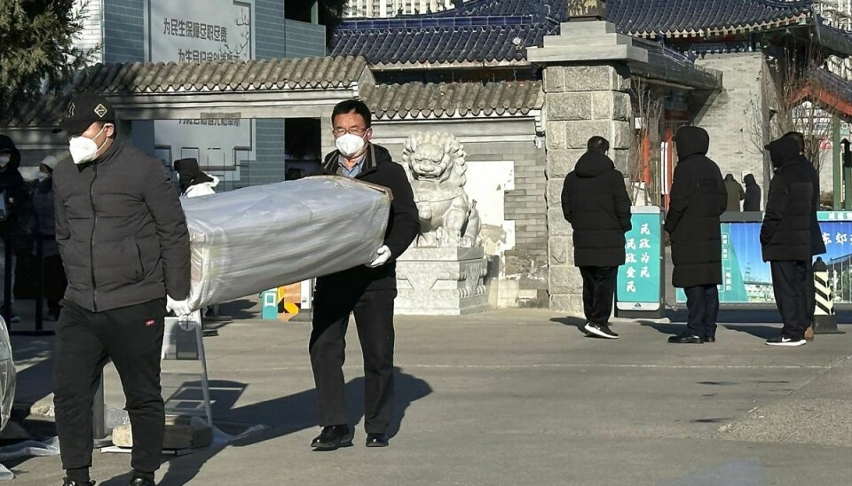 Mænd bærer en kiste ud fra et krematorium i den kinesiske hovedstad, Beijing.