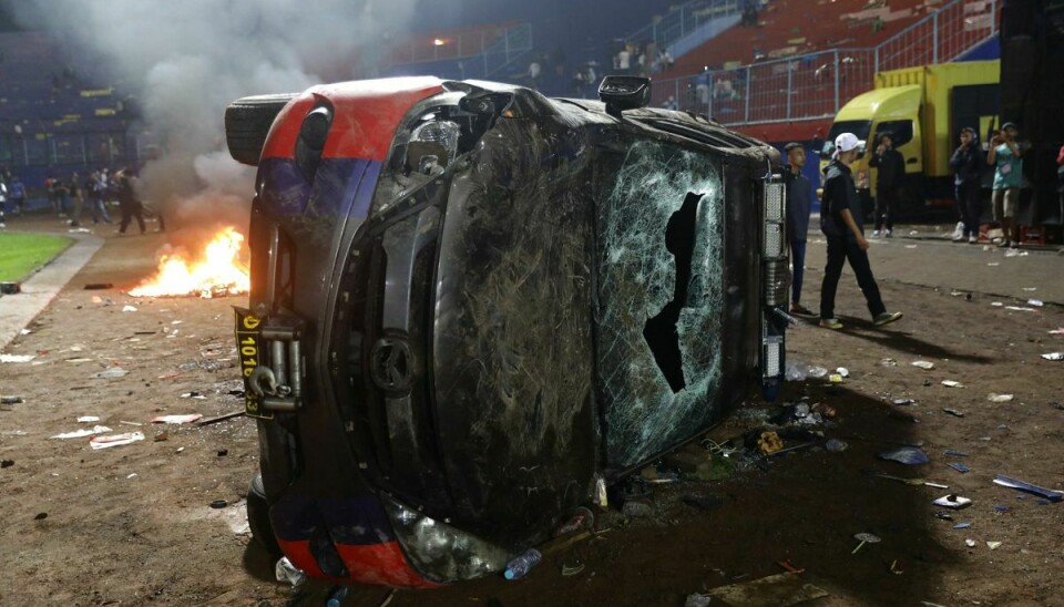 En udbrændt bil efterladt på gaden efter optøjer ved fodboldkamp i Indonesien. Mindst 129 meldes døde.