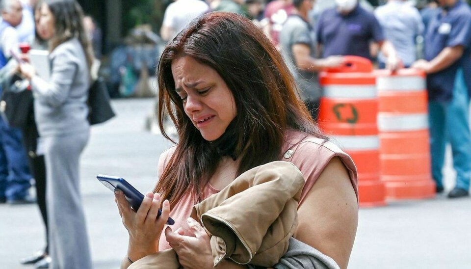 En chokeret kvinde forsøger at bruge sin mobiltelefon, efter jordskælvet, der fik bygninger i Mexico City til at ryste.