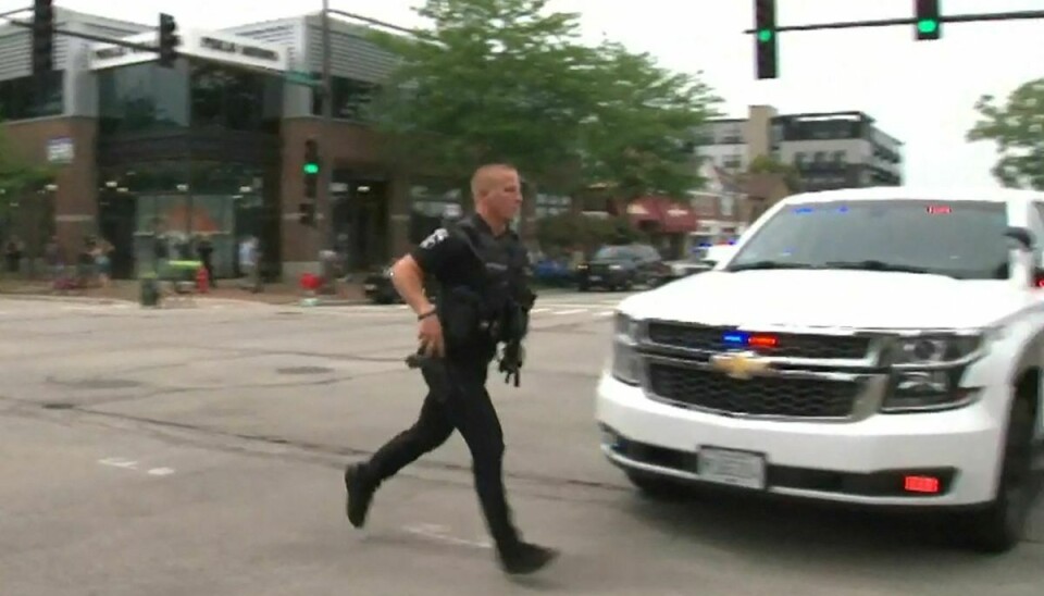 En politibetjent løber over en gade efter et skyderi ved en 4. juli parade ved Chicago-forstaden Highland Park, Illinois.