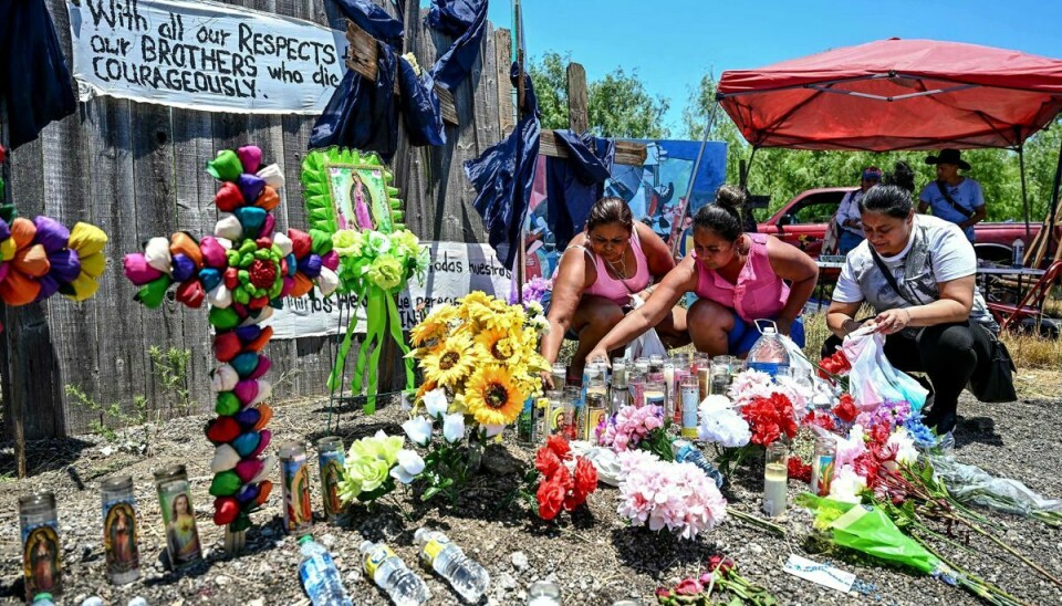 Sørgende lægger blomster og tænder stearinlys ved et mindesmærke nær San Antonio i Texas, hvor 53 migranter mandag blev fundet døde i en lastbil.