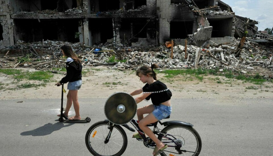 To børn cykler forbi en ruin af en bygning i Tjernihiv-regionen, der flere gange er blevet ramt af russiske angreb. Lørdag melder Ukraines hær om kraftig beskydning fra hviderussisk territorium.