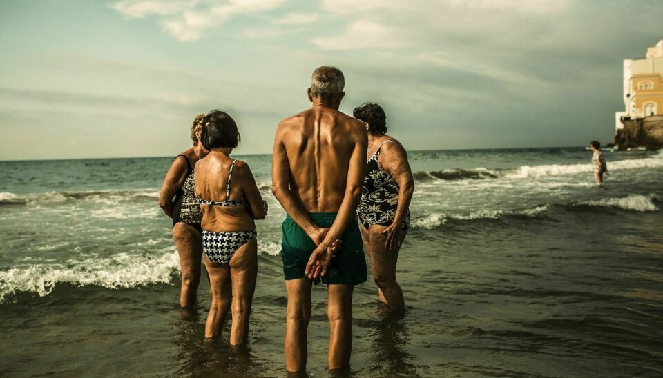Strand i middelhavsbyen Sitges, syd for Barcelona. Fire spanier taler sammen stående i vandet for at blive kølet ned og kunne udholde temperaturen der er over de 30 grader