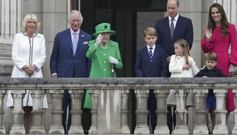 Fra Buckingham Palace' balkon vinker dronning Elizabeth søndag til de mange tusinde mennesker, der har samlet sig foran paladset. Hun er omgivet af kronprins Charles og hendes nærmeste familie.