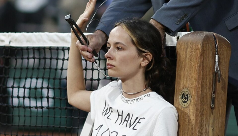 En kvindelig klimademonstrant binder sig selv til nettet ved French Open. En kvindelig klimademonstrant binder sig selv til nettet ved French Open.