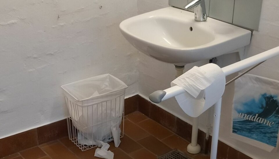 Affaldsbeholderen på kirketoilettet er blevet revet ud af væggen. Affaldsbeholderen på kirketoilettet er blevet revet ud af væggen.