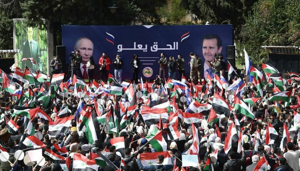 Syriske studenter vajer med syriske, russiske og palæstinensiske flag under en plakat med portrætter af den syriske præsident Bashar al-Assad og den russiske præsident Vladimir Putin, efter den russiske invasion af Ukraine.