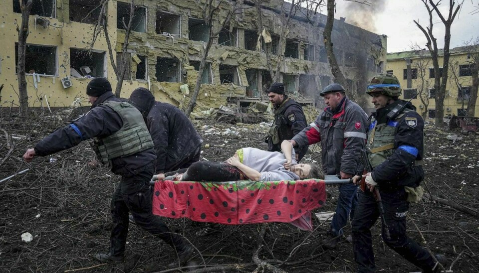 Ukrainske nødhjælpsarbejdere og frivillige bærer en såret gravid kvinde fra den fødeklinik, hvor hun skulle have født, men den blev bombarderet af russerne. Kvinden og babyen døde efterfølgende.