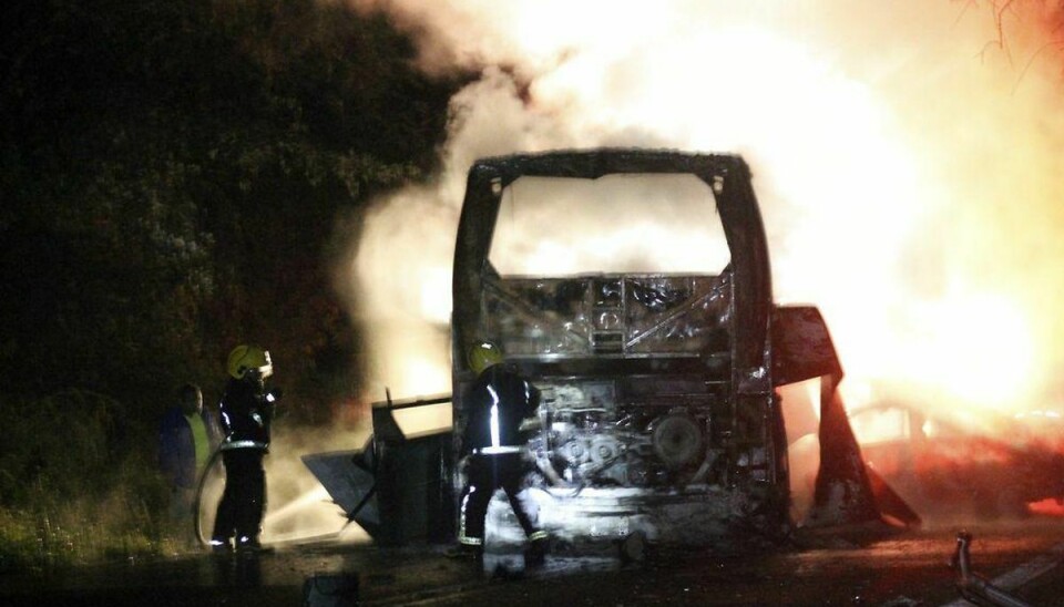 En brandmand forsøger at slukke branden i den mexicanske bus, der brød i brand efter en voldsom trafikulykke. Foto: Scanpix