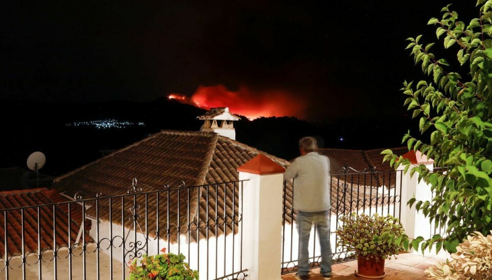 En mand betragter skovbranden nær Estepona i Spanien fra sin altan.