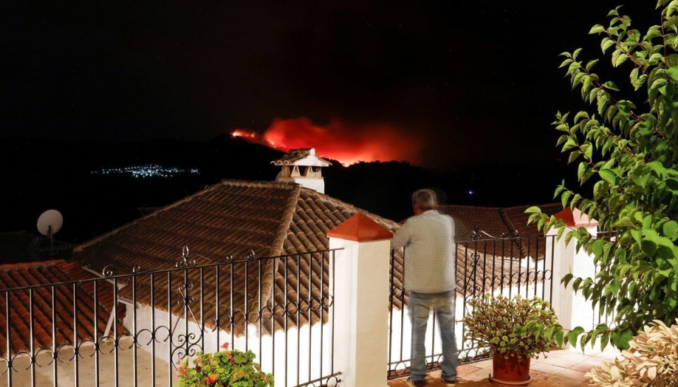 En mand betragter skovbranden nær Estepona i Spanien fra sin altan.