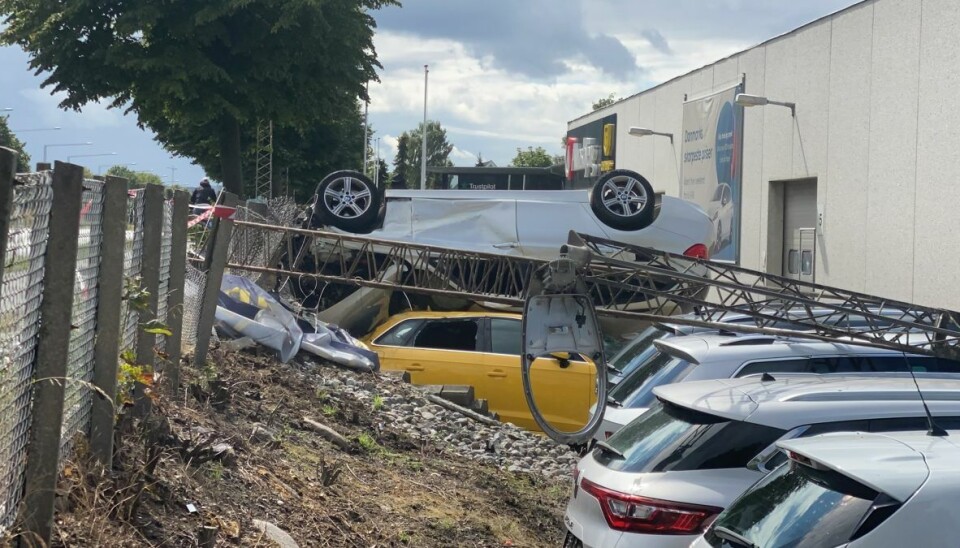 Den hvide bil kørte ind over hegnet og landede på flere biler hos en bilforhandler. Tre er kommet til skade under ulykken.