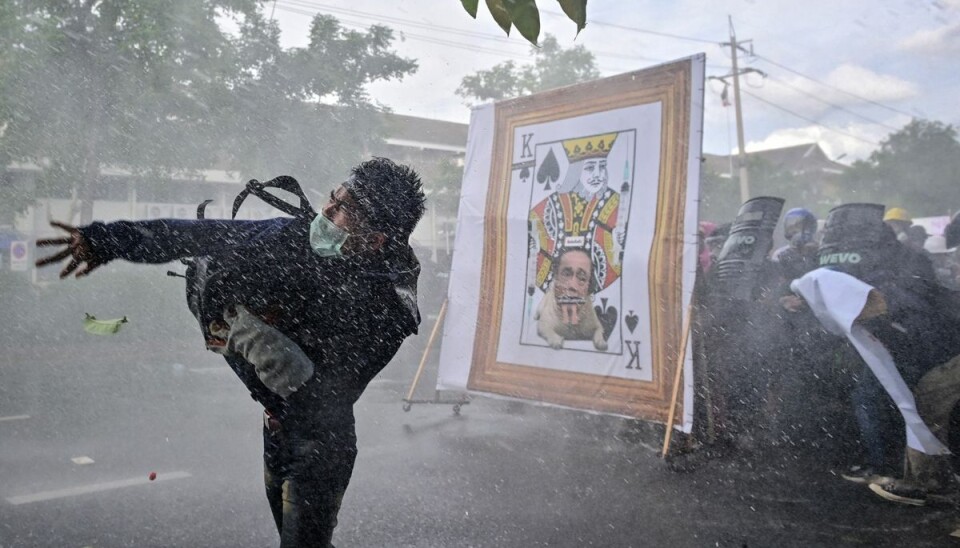 En demonstrant kaster et objekt mod politiet, mens andre går i dækning under kampe mellem demonstranter og politi i Bangkok.