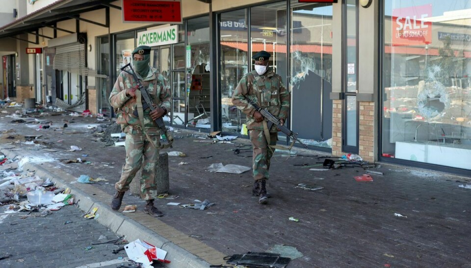 Soldater på patrulje går forbi adskillige butikker, som allerede er blevet plyndret under optøjer efter fængslingen af ekspræsident Jacob Zuma.