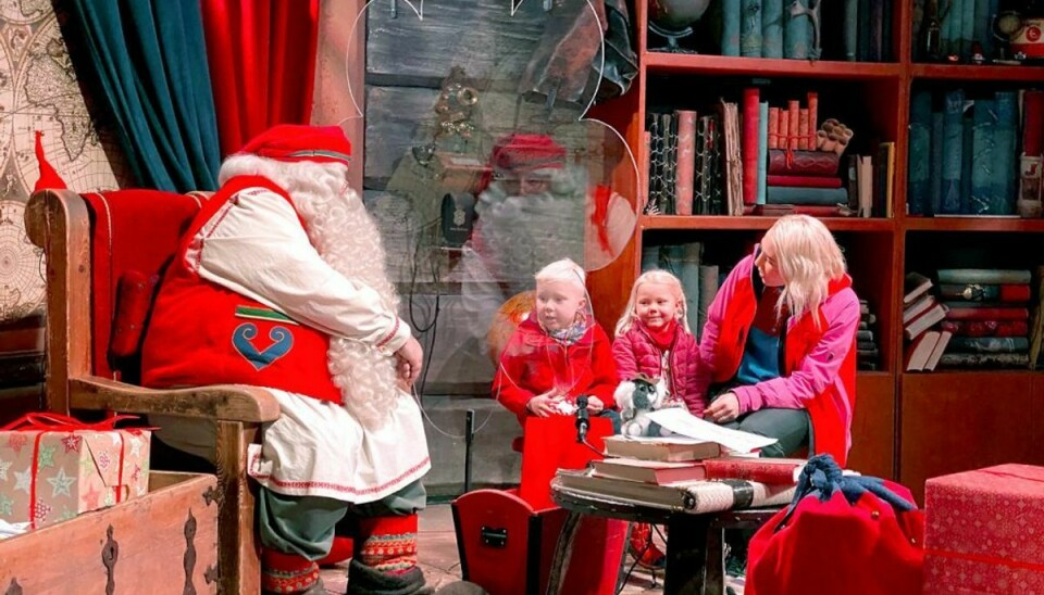 Børnene Edvin, Elsa og deres mor Anu mødtes med julemanden, dog adskilt af en plexiglasrude. Foto: Scanpix/Attila Cser