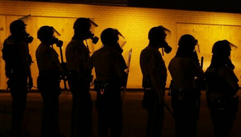 Politiet ser til, efter at tåregas blev anvendt mod demonstranter i Ferguson, Missouri, søndag aften lokal tid. Også mandag aften er tåregas blevet smidt mod demonstranterne, der protesterer over drabet på en 18-årig sort mand. Foto: Charlie Riedel/AP